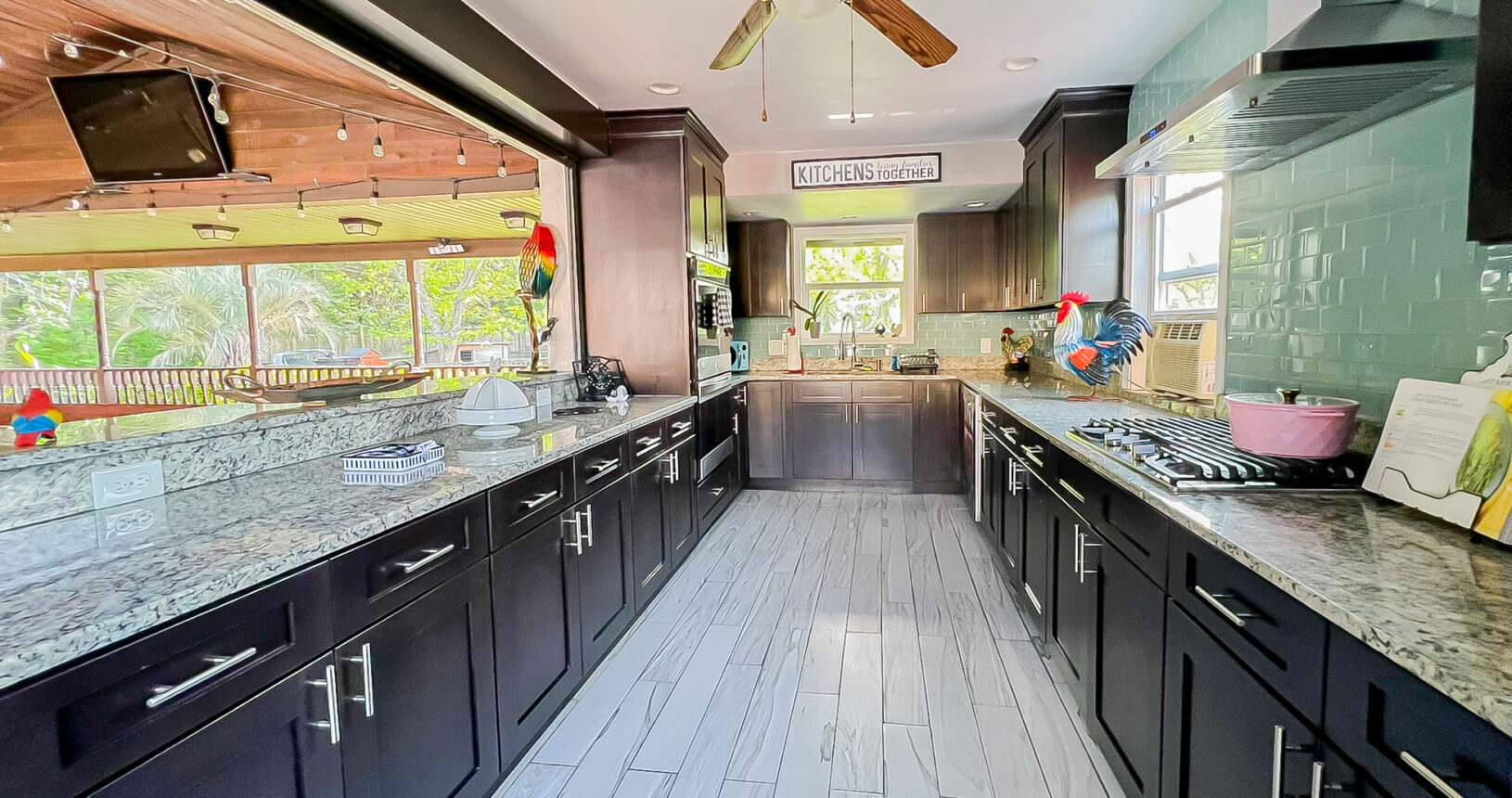 Pavilion gourmet kitchen with dark cabinets, granite counters, gas stove, and green subway tile backsplash at Palazzo Guest House