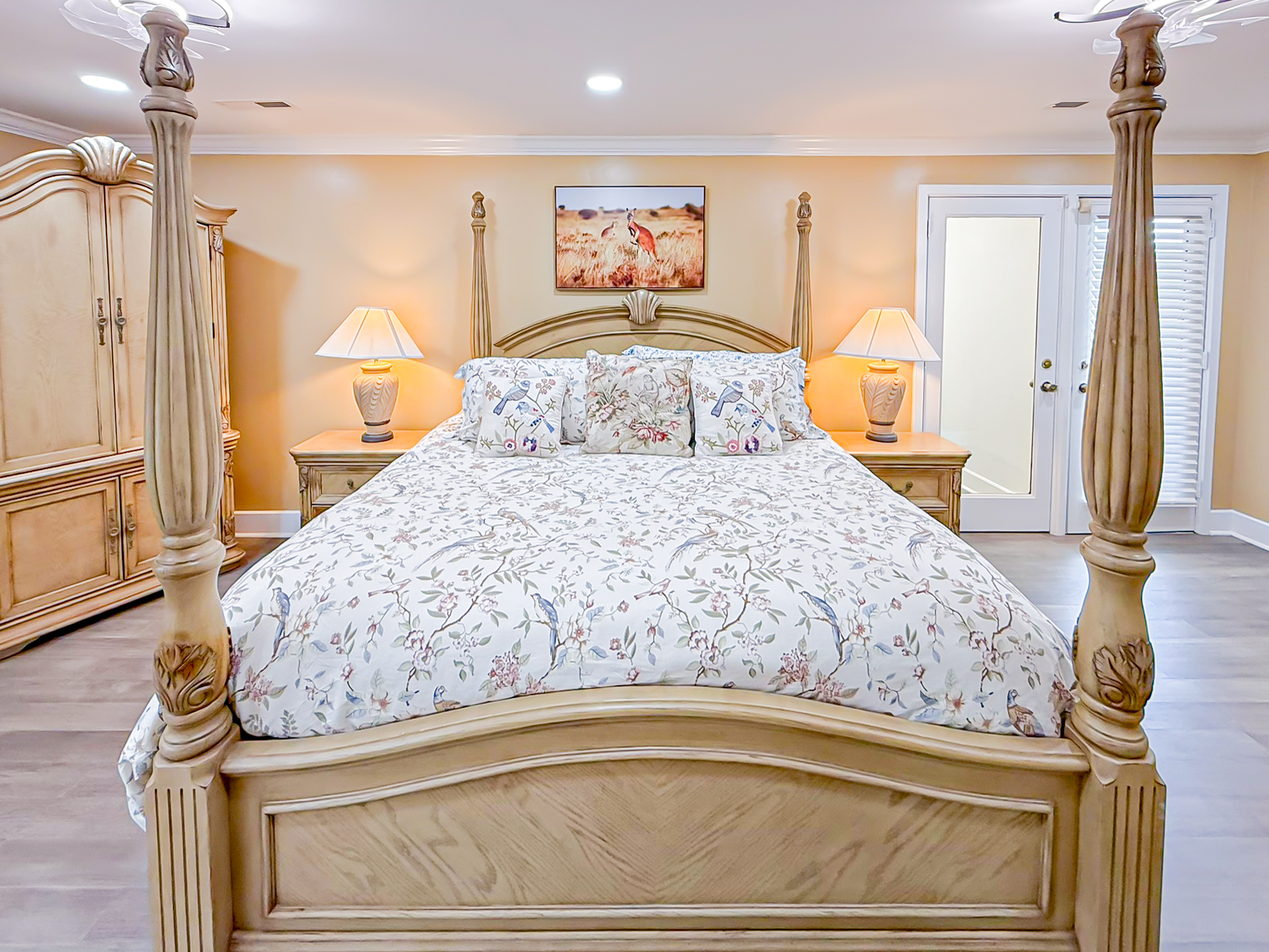 Elegant king suite with carved four-poster bed, floral linens, matching nightstands and lamps at Palazzo Guest House in Leland, NC